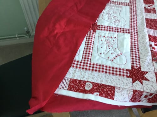 Close-up of the customer's red Plain Polycotton Fabric being used as the backing for a handmade quilt.