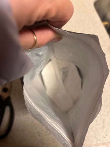 Customer holding open a bag of Melt powder, showing it is less than half full.