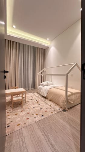 Customer's white House Kids Bed set up in a child's bedroom next to a small wooden table.