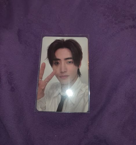 Customer's Enhypen Sunghoon photocard in a clear sleeve, showing the artist in a white shirt making a peace sign.