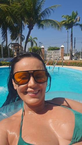 Cliente sorrindo em uma piscina, usando os Óculos Marino com lentes alaranjadas.