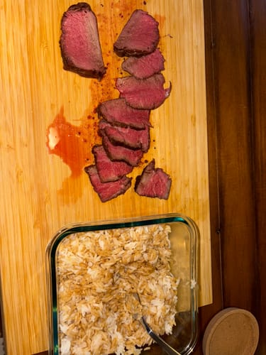 Reviewer's cooked USDA Prime Filet Mignon Steak, sliced on a cutting board to reveal a juicy red center.