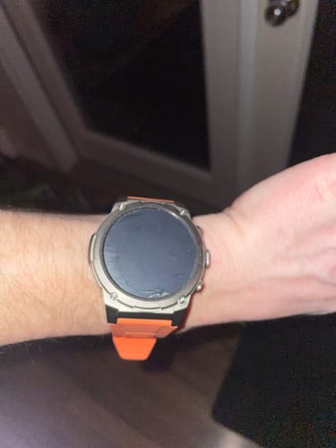 Reviewer's smartwatch with a silver case and an orange band on their wrist.