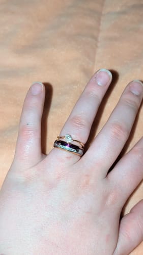 Close-up of a reviewer's hand wearing the Guardian ring with a purple inlay, stacked with another ring.