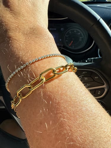 Reviewer wearing the Luna Bracelet Bundle, featuring a gold link and a sparkling tennis bracelet, on their wrist in a car.