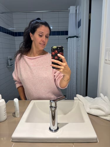 Reviewer taking a mirror selfie showing their phone in the black 'Juicy' case with a red cherry pattern.