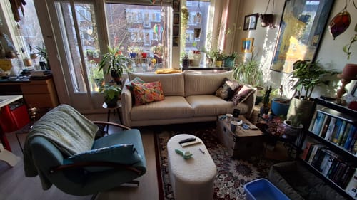 Recensent toont de crèmekleurige by fonQ Ribbon 3-zitsbank in een zonnige woonkamer.