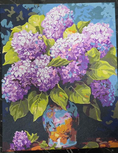 לקוח מציג את ציור הצביעה לפי מספרים שהשלים: זר פרחי לילך סגולים באגרטל.