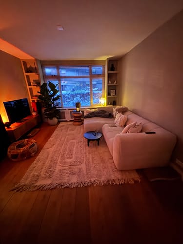 Recensent toont het zachte HKliving Tufted vloerkleed in een gezellige, warm verlichte woonkamer.