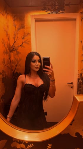 Reviewer taking a mirror selfie wearing the black Stretch Lace Stirrup Jumpsuit.