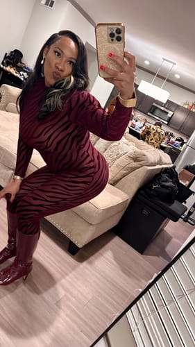 Customer crouching in a mirror selfie, wearing the red patterned Burnout Closed Toe Jumpsuit.