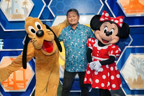 Reviewer wearing the blue "Merry Scary Teddy" shirt while posing between Disney's Pluto and Minnie Mouse characters.