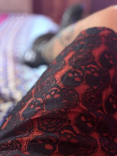 Close-up view of the red and black skull-patterned lace on the reviewer's gothic pencil dress.