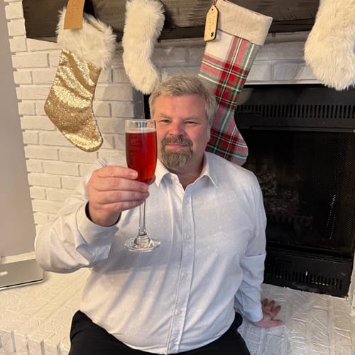Customer wearing the light grey Gin Joint Jubilee dress shirt, raising a glass in front of a fireplace.
