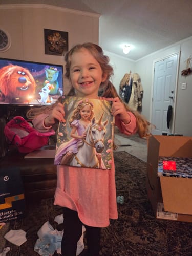 A customer's happy child holding up The Lavender Unicorn Princess artwork.