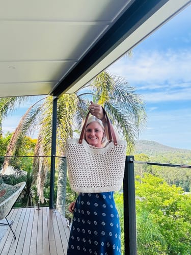 Customer holding up their finished CrochetPark™ Sunny Beach Tote on a sunny balcony.