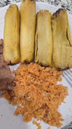 A customer's plate of four cooked Beef Tamales with rice and refried beans.