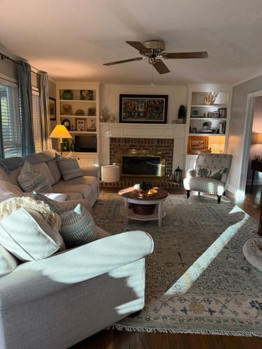 Customer's aqua and ivory wool area rug shown in their cozy den, with light streaming in from a window.