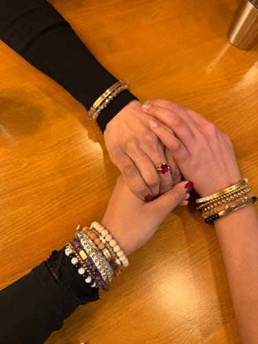 Two reviewers holding hands, each wearing the KIND HEART - FIERCE MIND - BRAVE SPIRIT beaded bracelet.