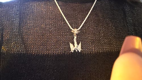 Customer wearing the silver Fallen Angel Pendant on a chain against a black knit top.