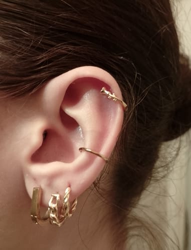 Photo d'un client montrant plusieurs boucles d'oreilles dorées reçues en bijou mystère, portées à l'oreille.