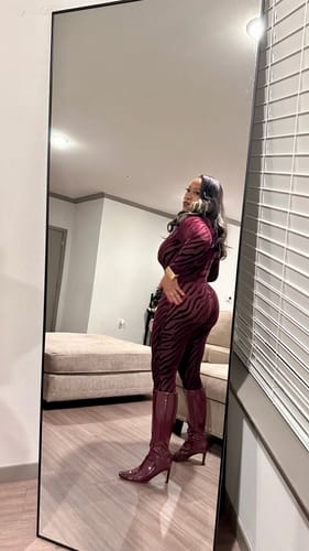 Reviewer's mirror selfie showing the side view of the patterned red Burnout Closed Toe Jumpsuit with matching boots.