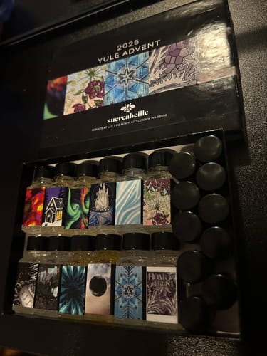 Customer's open Yule Advent Calendar box, showing rows of small glass bottles with colorful artistic labels.