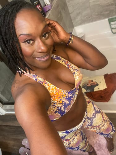 Reviewer in a bathroom wearing the colorful Chakra Regular Bra and matching leggings.