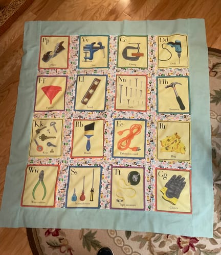 Customer's sewing project using the Construction Tools Fabric, which features alphabet cards with tools, sewn with a solid blue border.