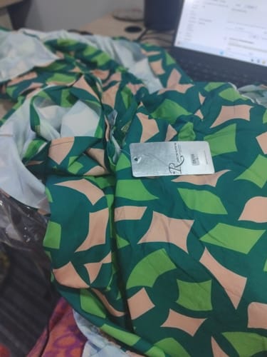 Reviewer's photo of the printed bodycon dress fabric, showing the green and pink abstract pattern received.