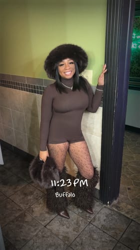 Customer posing in the brown Butter Turtleneck Contour Romper, styled with patterned tights and fuzzy accessories.