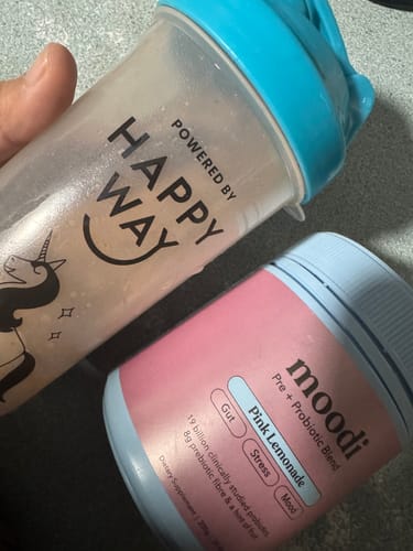 Customer's close-up of the pink moodi Pink Lemonade container next to a shaker cup holding the drink.
