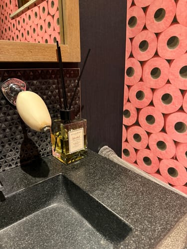 Recensent's Istanbul geurstokjes op een donkere wastafel in een badkamer, de fles is halfvol.
