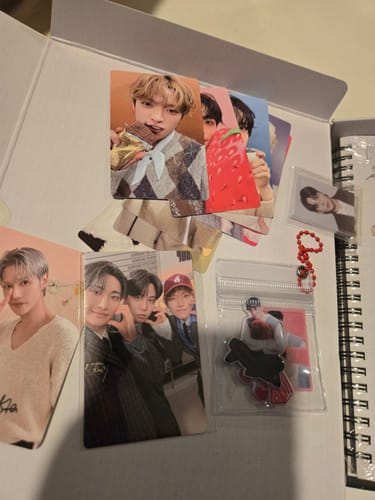 Customer displays the opened ATEEZ - 2026 SEASON'S GREETINGS box, showing various photocards and a spiral-bound book.