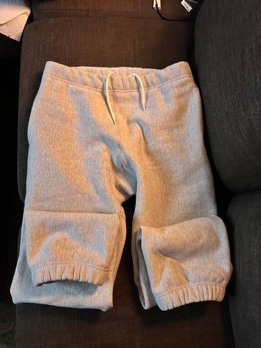 Customer's gray Terry Cloth Reverse Weave Sweatpants folded on a dark couch, showing the waistband and cuffs.