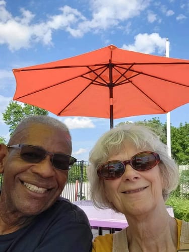 Reviewer who reports significant pain reduction with Colagene, smiling outdoors with his wife under an umbrella.