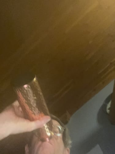 Reviewer drinking from their hand-hammered Pure Copper Water Bottle indoors.