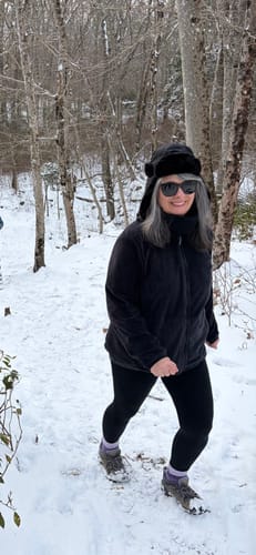 Customer walking through a snowy forest wearing black Stella Leggings.