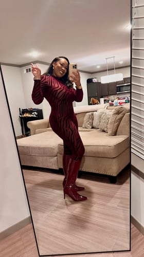Customer smiling in a mirror selfie, wearing the full-length red patterned Burnout Closed Toe Jumpsuit.