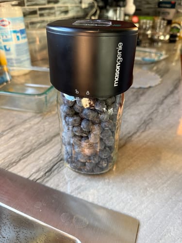 Reviewer's black Mason Genie Vacuum Sealer on a glass jar filled with fresh blueberries.