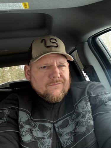 Customer in a car wearing a tan and brown trucker hat with a logo.