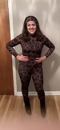 Reviewer posing indoors wearing the Naked Print Stirrup Jumpsuit with a matching headband and black boots.