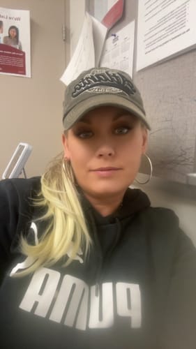 Reviewer wearing the blonde JuvaBun straight ponytail extension, styled with a baseball cap.