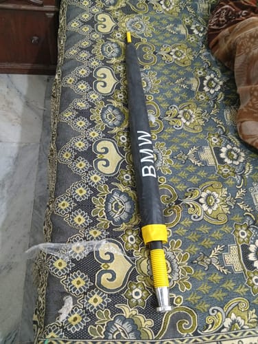 Customer's closed black BMW umbrella with a yellow handle, resting on a patterned surface.