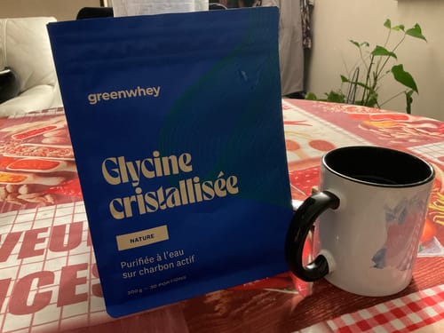 Photo d'un client montrant le sachet de Glycine cristallisée posé sur une table à côté d'un mug.
