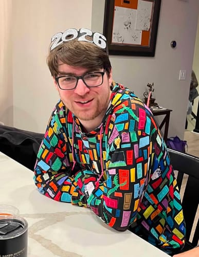 Customer smiling while sitting at a table wearing the colorful Monsters, Inc. 'Doors' performance hoodie.