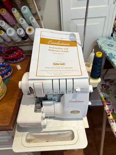 Customer's Babylock BLE8W-2 Evolution Instruction Manual resting on the corresponding serger machine.