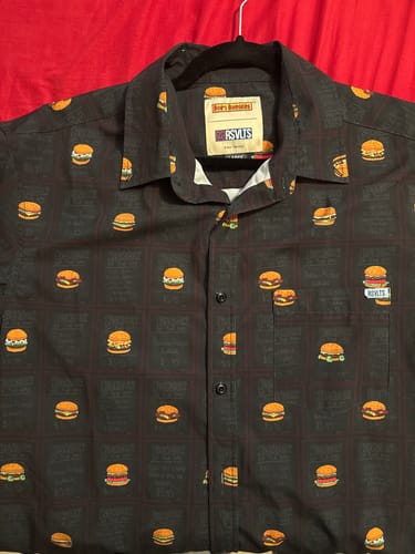Customer's dark Bob's Burgers 'Burgers of the Day' shirt on a hanger, showing the fun pattern of cartoon burgers.