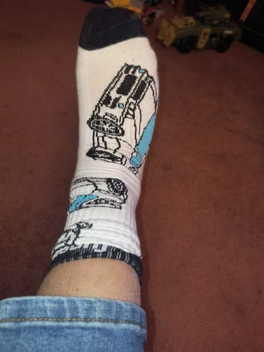 A reviewer wearing the white SKYLINE CREW SOCKS, showing the black heel and a graphic print on the ankle.