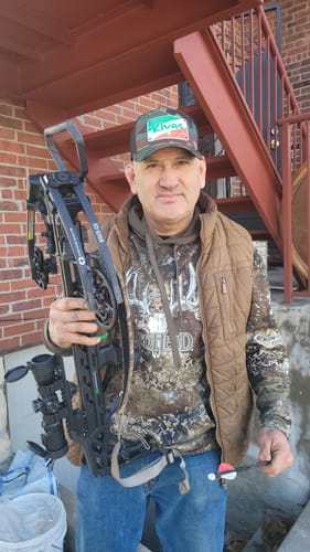 Customer wearing the camo Taheen Salsa Picante Custom Hat while holding a crossbow.
